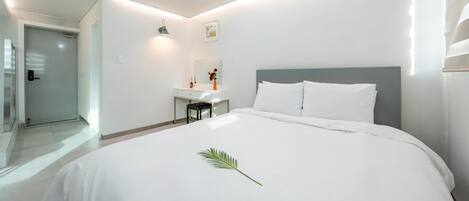 A modern hotel room with a large bed, a desk, and a bathroom.