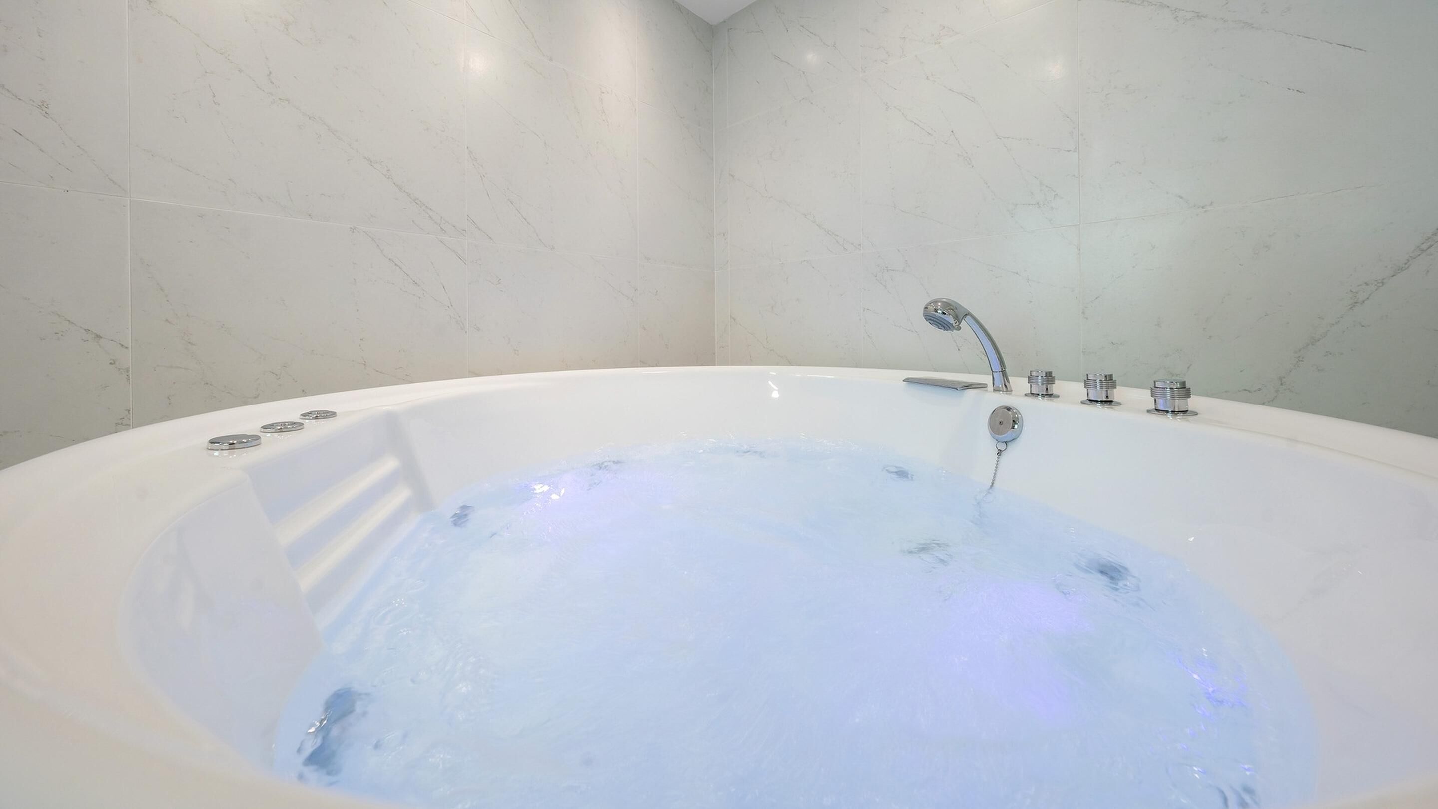 A modern bathroom with a large white bathtub, a showerhead, and a faucet.