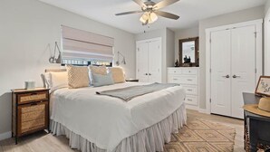 A bedroom with a bed, a ceiling fan, a dresser, a wardrobe, and a bedside table. - Luxury Waterfront Condo  Pool + Hot tub  Sleeps 4 (Spicewood)