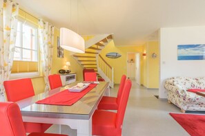 Ein Essbereich mit Tisch und Stühlen, eine Treppe und ein Bett mit Blumenmuster-Bettwäsche.