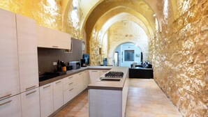 A modern kitchen with a central island, stone walls, and a vaulted ceiling. - Mixel Gozitan Villa and Pool (Sannat)