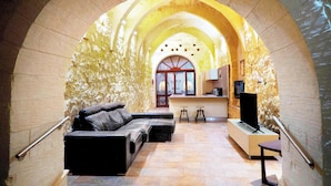 A modern interior with a curved ceiling, a sofa, a TV, and a bar area. - Mixel Gozitan Villa and Pool (Sannat)