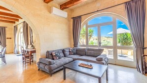 Ein Wohnzimmer mit Ecksofa, Couchtisch und einem Essbereich mit Stühlen und Tisch.