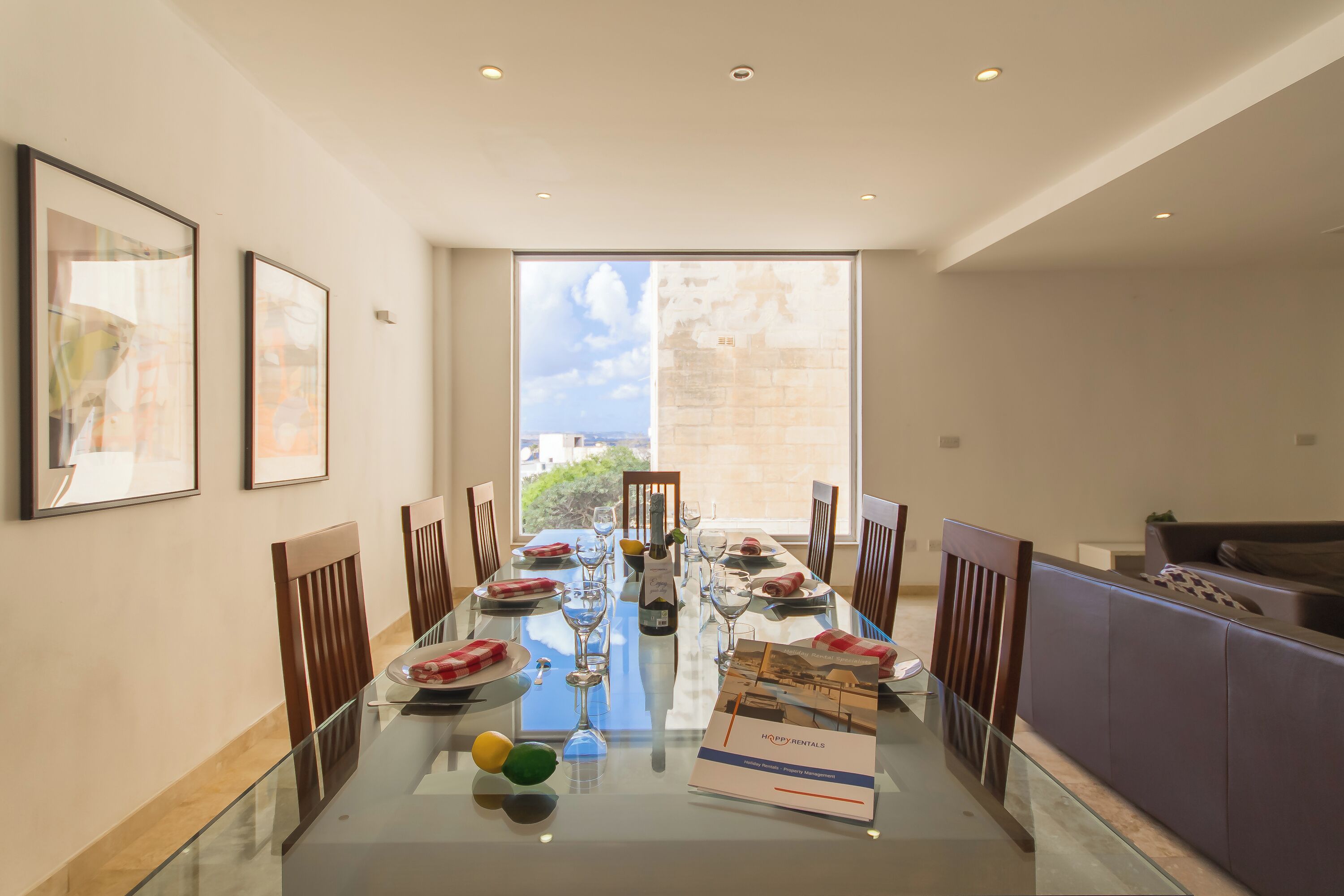 A dining area with a glass table, chairs, and a view of the city through large windows.
