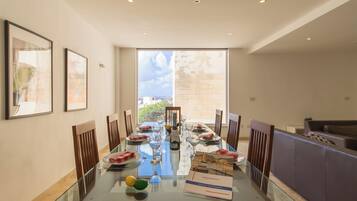 A dining area with a glass table, chairs, and a view of the city through large windows.