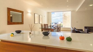 A modern kitchen with a large island, dining area with chairs, and a view of the outdoors. - Seaview Pool Dolmen Apt St Paul's Bay (St. Paul's Bay)