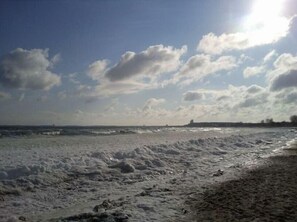 Enjoy the serene beach scene with a clear view of the ocean and distant landmass.