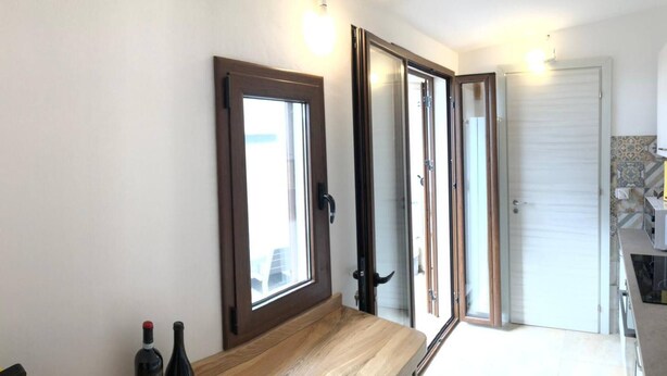A staircase leading to a room with a sliding glass door, a small table with bottles, and a tiled backsplash. - A La Batìa - Ospitalità Diffusa (Partanna)