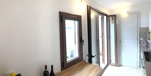 Una escalera conduce a una habitación con puerta de vidrio corrediza, una pequeña mesa con botellas y un salpicadero de azulejos.