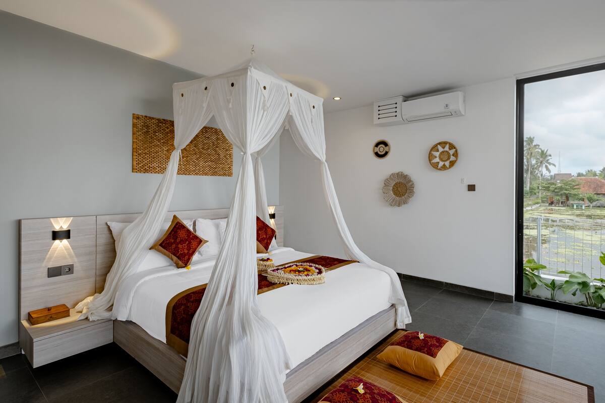 A modern bedroom with a canopy bed, bedside tables, decorative wall art, and a view of the outdoors.