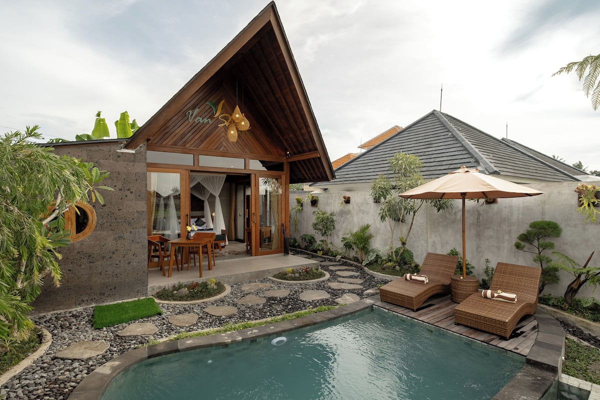 A modern house with a pool, wooden deck, and outdoor furniture.