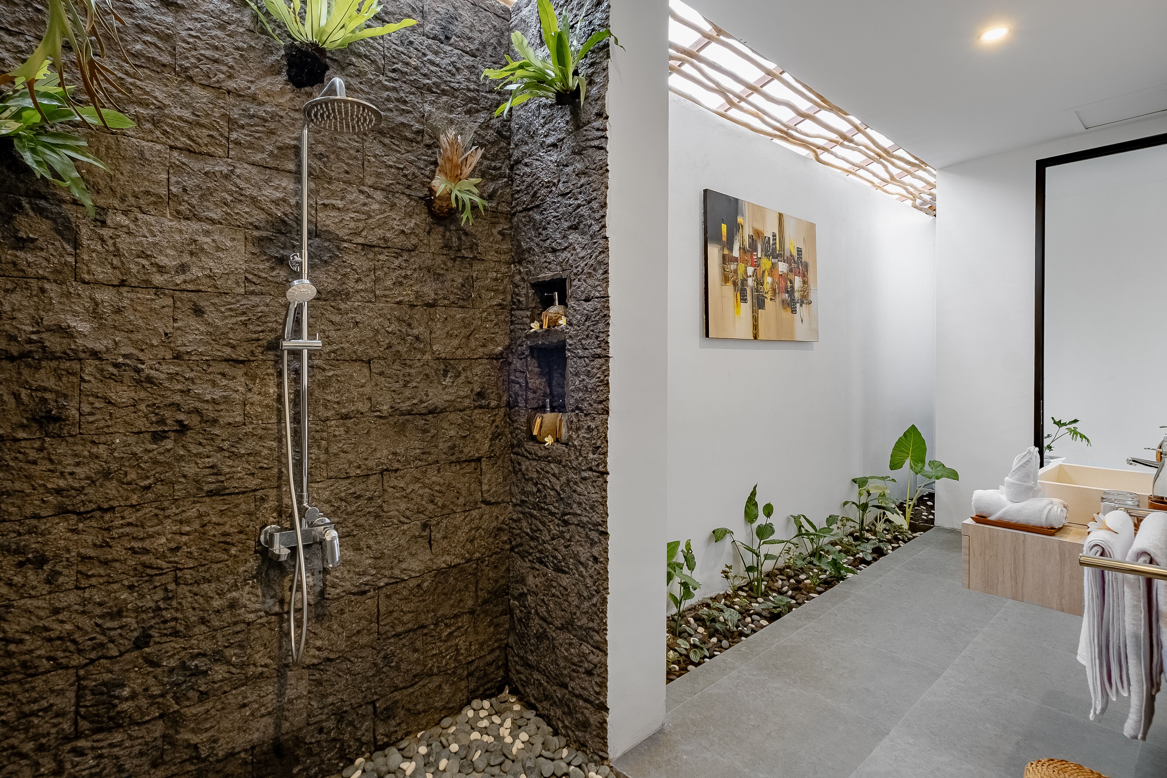 Un baño moderno con pared de piedra, ducha, plantas y un diseño minimalista.