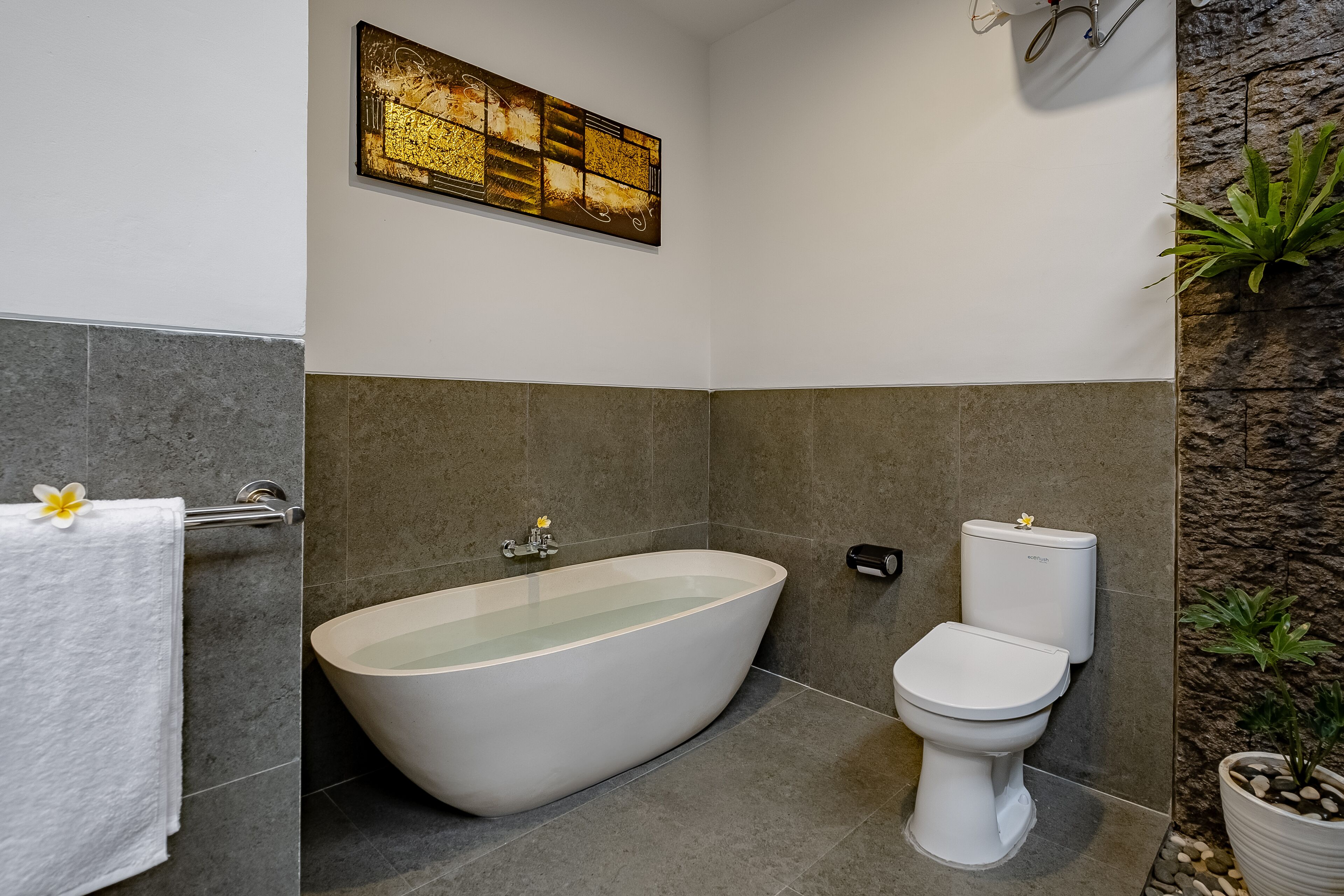 Un baño moderno con una bañera independiente, un inodoro y un lavamanos montado en la pared.