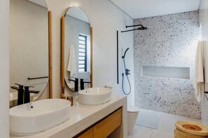 Een moderne badkamer met twee wastafels, een grote spiegel, een douche en een gestructureerde wand.