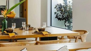 A dining area with a large window, a hanging light fixture, and a plant on the table. - 3 bedroom villa nestled in nature (Black River Gorges)