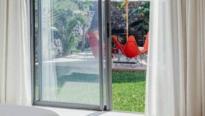 Une chambre avec un lit et une porte-fenêtre coulissante donnant sur un espace extérieur aménagé avec une table et des chaises.