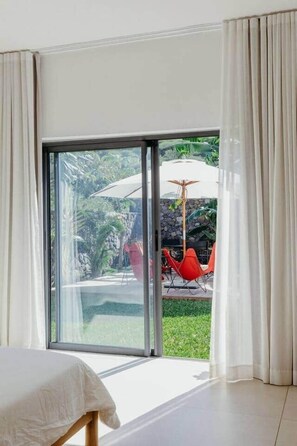 Een kamer met een bed en een schuifdeur die uitkomt op een terras met een tafel en stoelen.