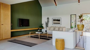 Un salon moderne avec un canapé, une table basse, un téléviseur et une grande fenêtre.