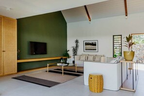 Een moderne woonkamer met een bank, een salontafel, een televisie en een groot raam.