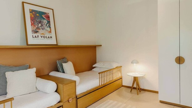 A bedroom with a bed, a bedside table, a lamp, a wardrobe, and a poster on the wall. - 3 bedroom villa nestled in nature (Black River Gorges)