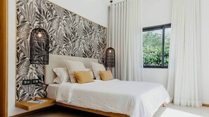 Une chambre moderne avec un lit, du linge de lit blanc, un mur à motifs et une fenêtre avec des rideaux.