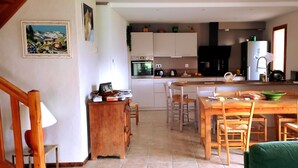 A kitchen with white cabinets, a dining table with chairs, and a refrigerator.
