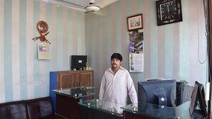 A reception area with a desk, computer, and a clock on the wall. - Mehran Hotel (Rawalpindi)