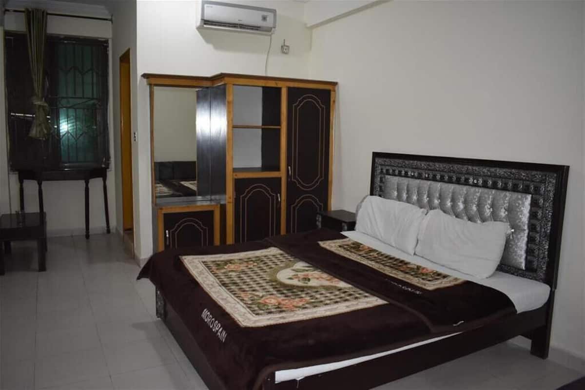 A bedroom with a bed, a wardrobe, and a desk.