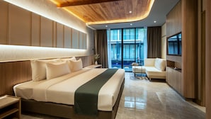 A modern hotel room with a large bed, a seating area, and a view of the pool. - Luminous Resort & Spa by Areca (Kathu)