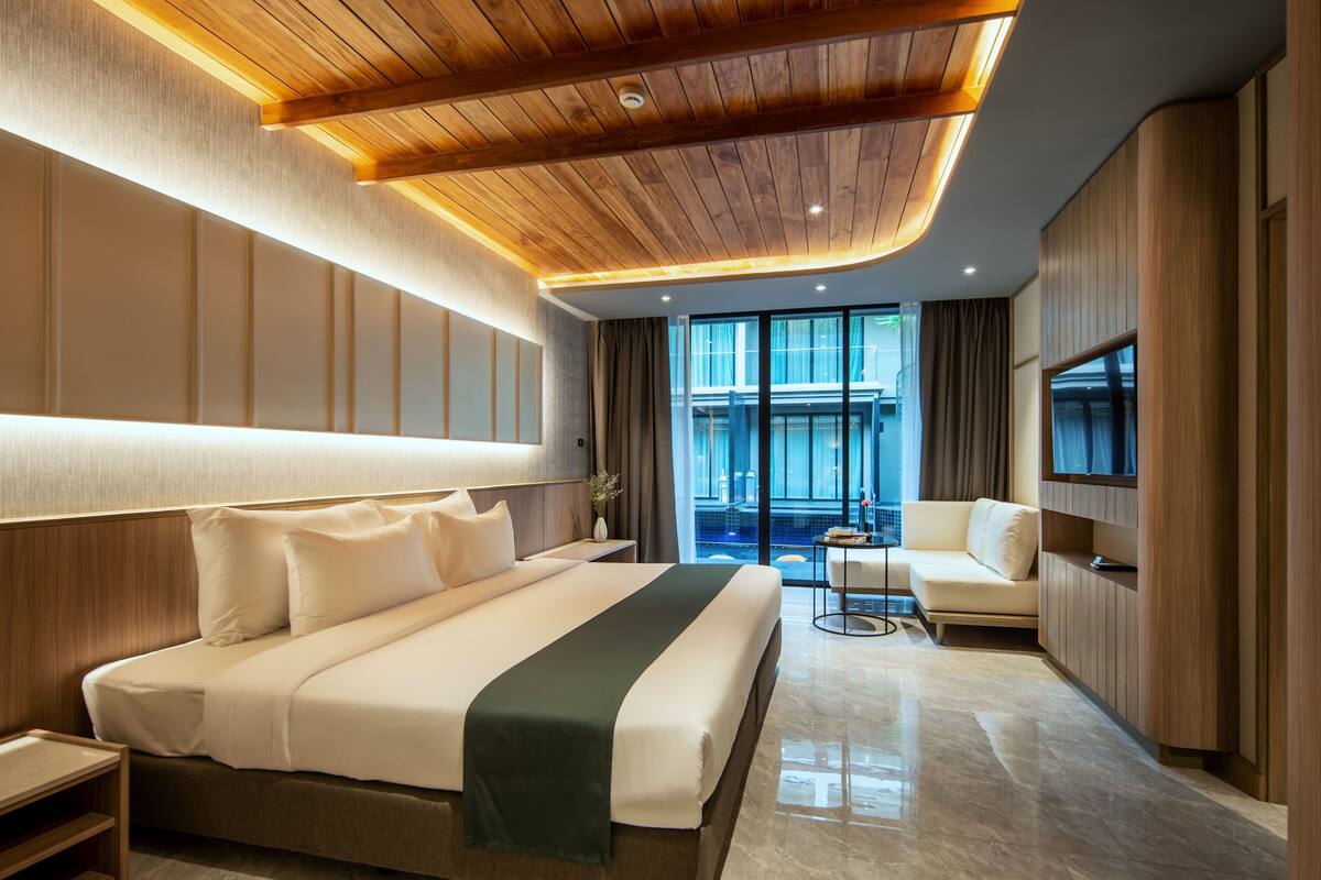 A modern hotel room with a large bed, a seating area, and a view of the pool.