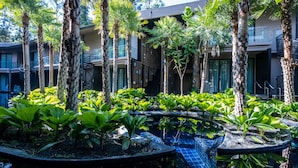 A pool area with palm trees and a modern building in the background. - Luminous Resort & Spa by Areca (Kathu)
