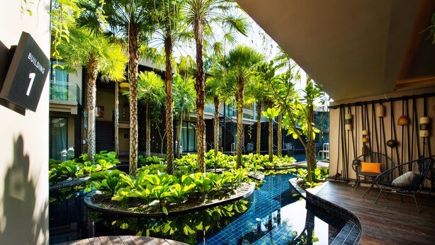 A modern indoor garden with a pool, wooden deck, and seating area. - Luminous Resort & Spa by Areca (Kathu)