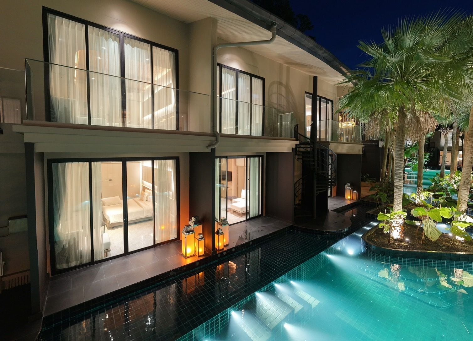 A multi-story hotel with a swimming pool, large windows, and a staircase.