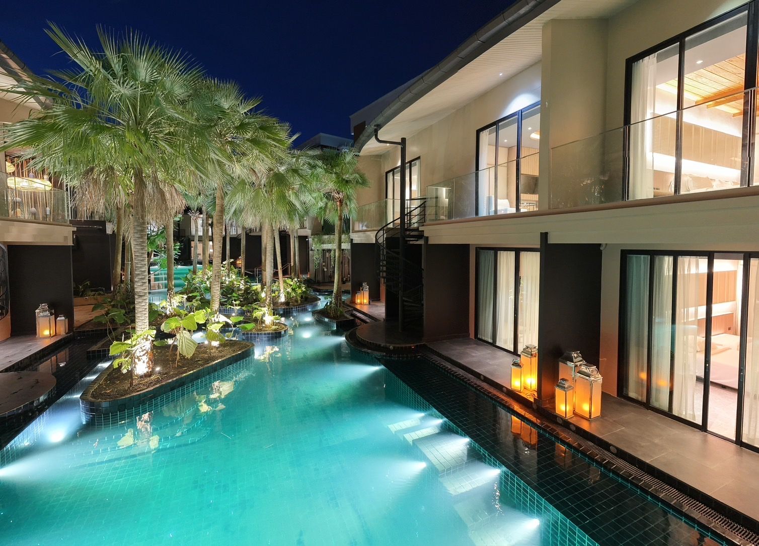 A swimming pool with a glass barrier, surrounded by palm trees and indoor lighting.