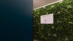 Una pared con un cartel que indica la disponibilidad de habitaciones y una pared verde exuberante con plantas.