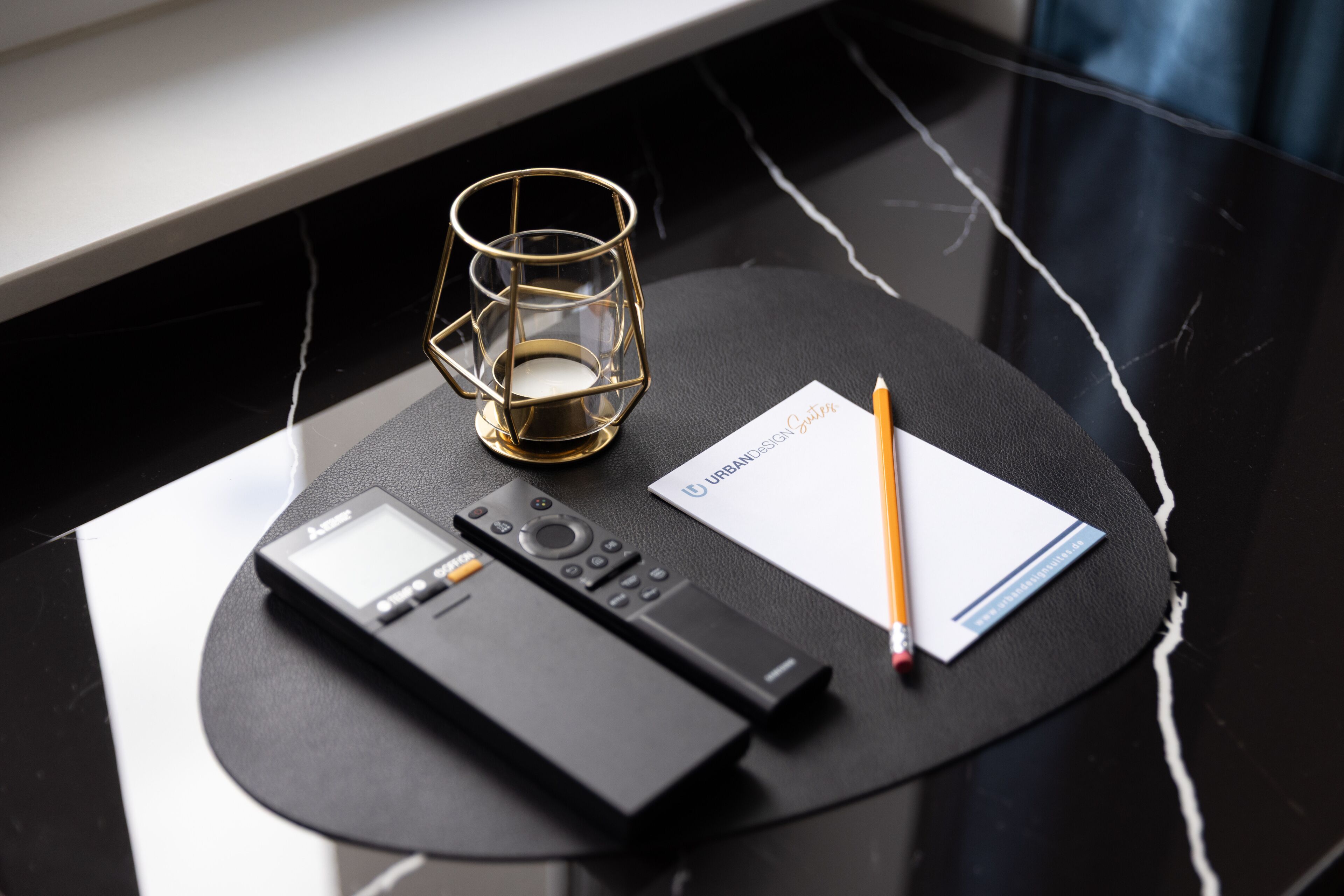 Ein schwarzer Marmortisch mit einem Laptop, einem Smartphone, einem Glas und einem Notizbuch.
