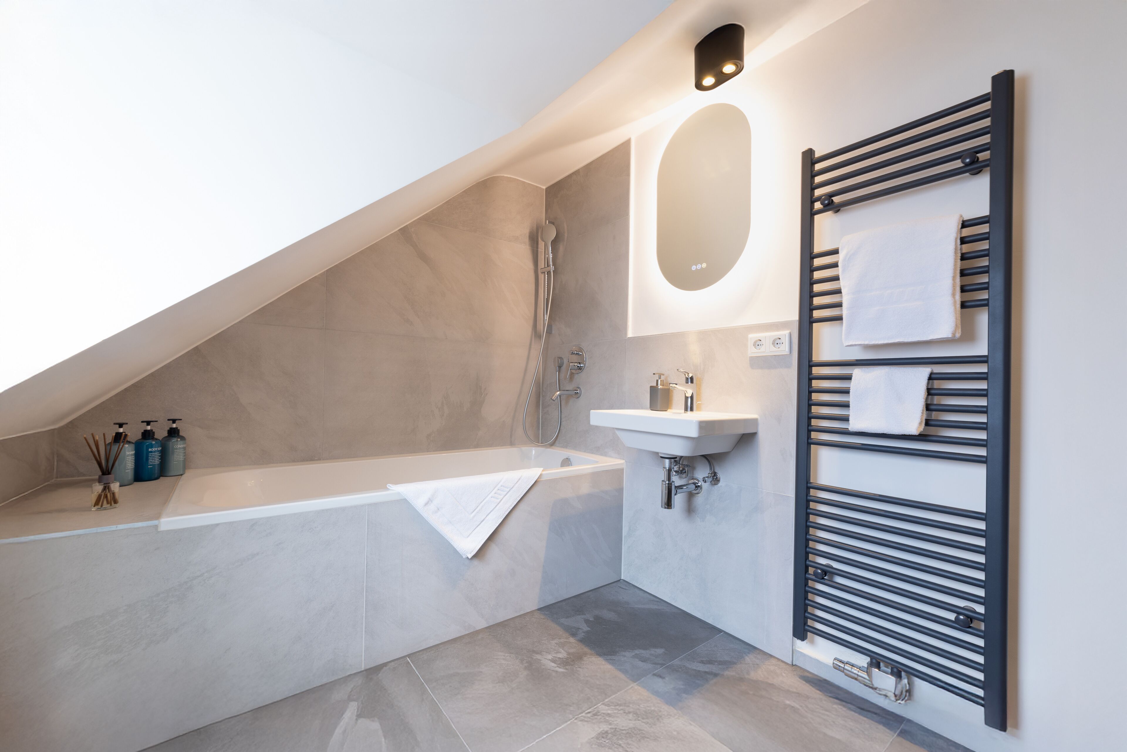 Een moderne badkamer met een vrijstaand bad, een ingebouwd wastafelmeubel en een handdoekhouder.