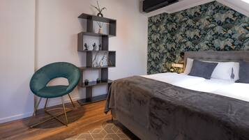A modern bedroom with a grey upholstered bed, a teal chair, and a wall-mounted shelf with decorative items.