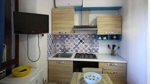 Une cuisine compacte dotée d’une cuisinière intégrée, d’un évier et d’armoires en bois.