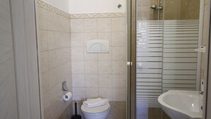 Une petite salle de bain comprenant des toilettes, une douche à parois de verre et un lavabo.