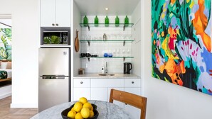 A modern kitchen with white cabinets, a built-in microwave, and a glass shelf unit. - Villa Jabula  (Seminyak)