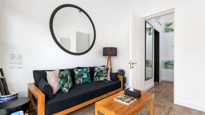 A modern living room with a black sofa, a round mirror, a wooden coffee table, and a lamp. - Villa Jabula  (Seminyak)