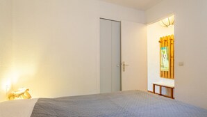 Quarto com cama, porta e espelho fixado na parede.