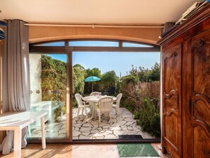 Une terrasse avec une table et des chaises, un meuble en bois et une porte vitrée donnant sur l’extérieur.