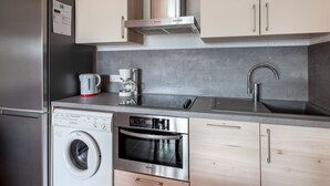 Uma cozinha moderna com eletrodomésticos de aço inoxidável, forno embutido, cafeteira e máquina de lavar.