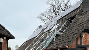 En bygning med facade i mursten, en metal trappe op til taget og solpaneler på taget.