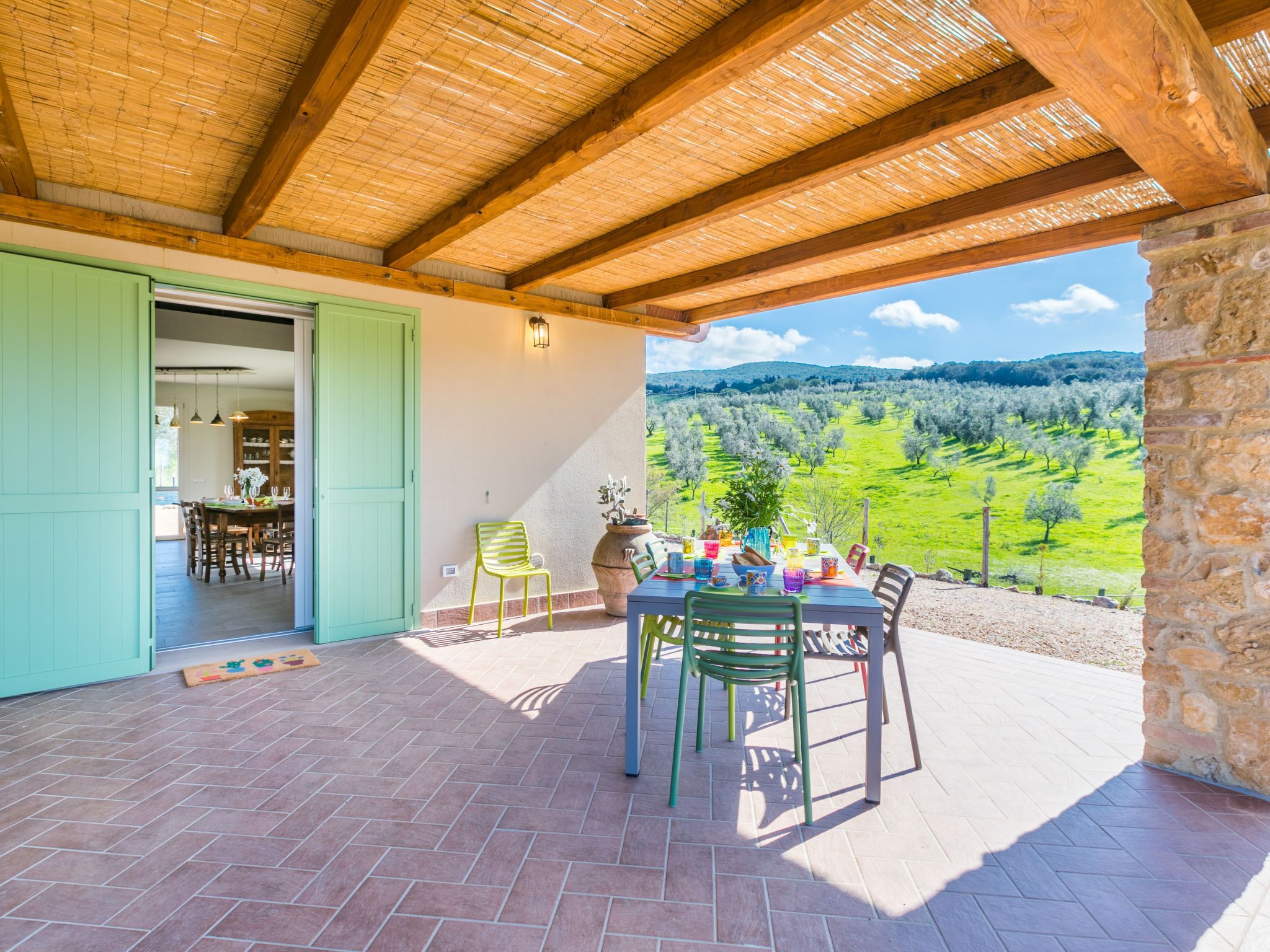 Une terrasse extérieure avec une table dressée pour le repas, une chaise et une vue sur un paysage verdoyant.