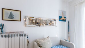 A room with a white radiator, a chair with a blue patterned cushion, and a wall-mounted light fixture with hanging bulbs. - Casa e mare by Interhome (Cecina)