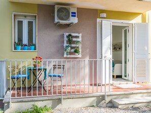 A balcony with a table and chairs, potted plants, and an air conditioning unit. - Casa e mare by Interhome (Cecina)