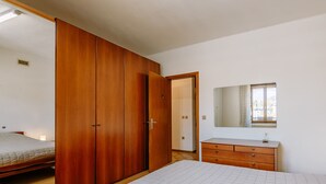 A bedroom with a bed, a wooden wardrobe, a dresser, and a mirror. - Apartment Fruet by Interhome (Lago di Caldonazzo)